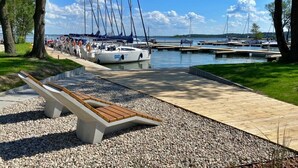 Un puerto deportivo con barcos amarrados, una pasarela de madera y un banco.
