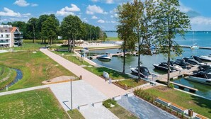 Un puerto deportivo con barcos amarrados, un sendero para caminar y una zona verde con árboles.