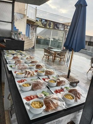 A buffet setup with various food items and a view of a building with a staircase. - Blue Pyramids Eyes Hotel (Giza)
