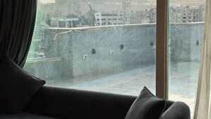 Quarto com uma grande janela que dá para uma área de construção com uma estrutura em forma de pirâmide.
