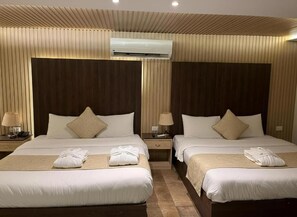 A hotel room with two beds, a wooden ceiling, an air conditioning unit, and a nightstand with a lamp. - Blue Pyramids Eyes Hotel (Giza)