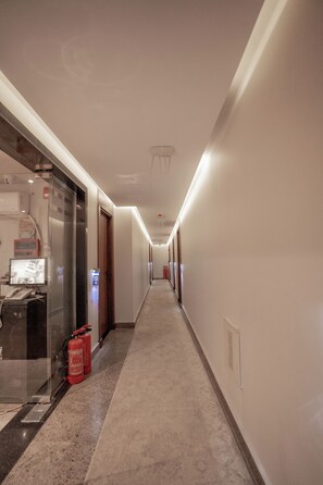 A hotel hallway with a carpeted floor, doors on the left, and a fire extinguisher on the right. - Blue Pyramids Eyes Hotel (Giza)