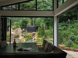 En modern inredning med ett matområde, en soffa och utsikt över en vacker, naturlig utomhusmiljö.