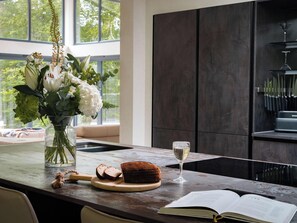 A kitchen counter with a loaf of bread, a wine glass, and a book.