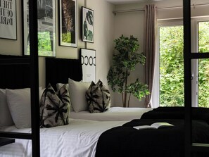 A bedroom with a bed, pillows, a plant, and framed pictures on the wall. - Heilan Roo (Pitlochry)