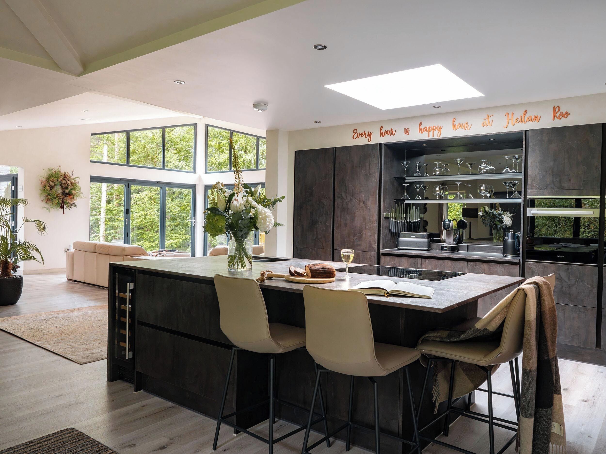 A modern kitchen with a central island, bar stools, and a view of the outdoors.