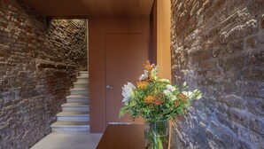 A hallway with a staircase, a door, and a vase with flowers. - Palazzetto San Stin (Venice)