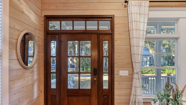 A wooden door with glass panels, a mirror above it, and a window with a view of greenery. - Beautiful 3 bed - 3 bath home located in Village Oaks (Saint Simons Island)