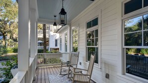 A covered porch with wooden chairs, a table, and hanging lanterns. - Beautiful 3 bed - 3 bath home located in Village Oaks (Saint Simons Island)