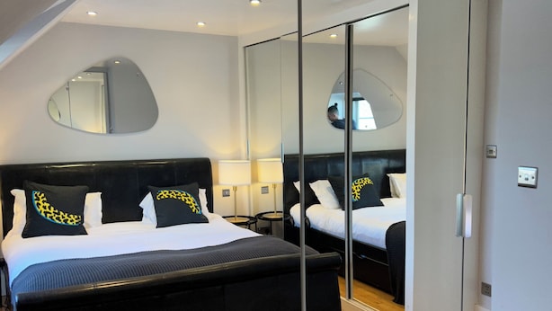 Ein modernes Schlafzimmer mit einem großen Bett, einem Spiegel und Holzboden.