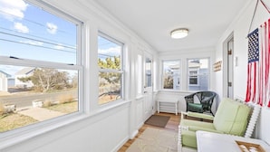 A sunlit room with large windows, a green chair, a white table, and an American flag decoration.