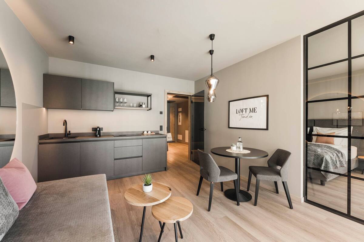 A modern, compact living space with a kitchenette, a dining area, and a bedroom.