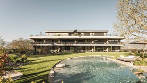 Un immeuble moderne à plusieurs étages, doté d’une piscine, entouré d’une pelouse et d’un jardin bien entretenus.