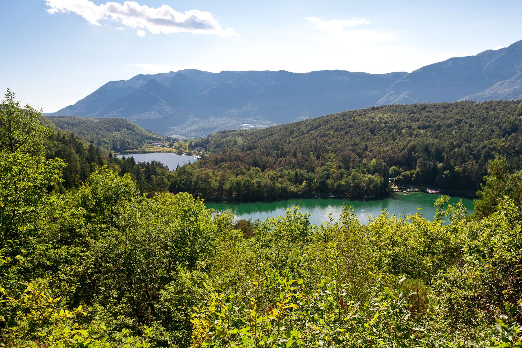 A mountainous landscape with a lake surrounded by dense forest and hills.