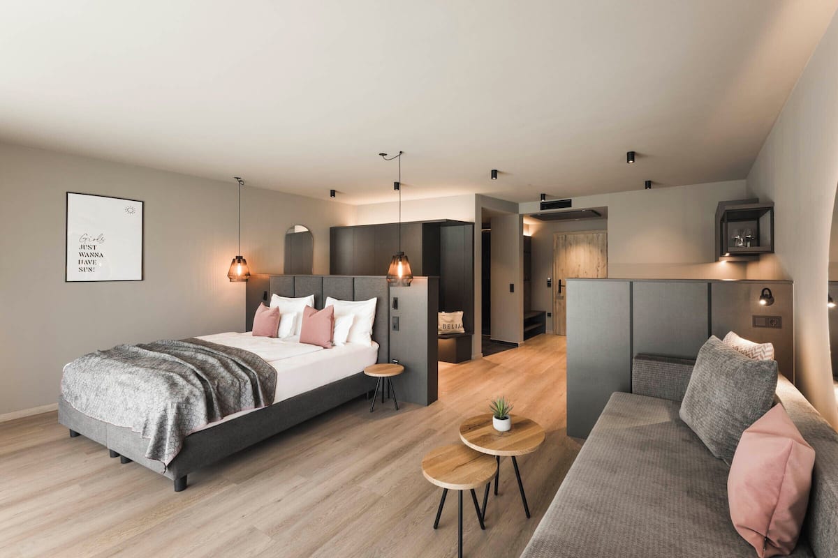A modern bedroom with a bed, a sofa, a small table, and a TV.
