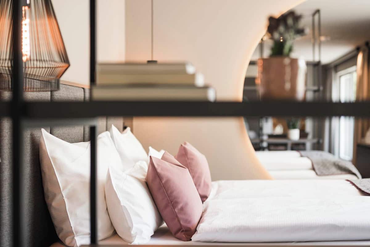 A modern hotel room with a bed, bedside table, lamp, and a view of the room's interior.