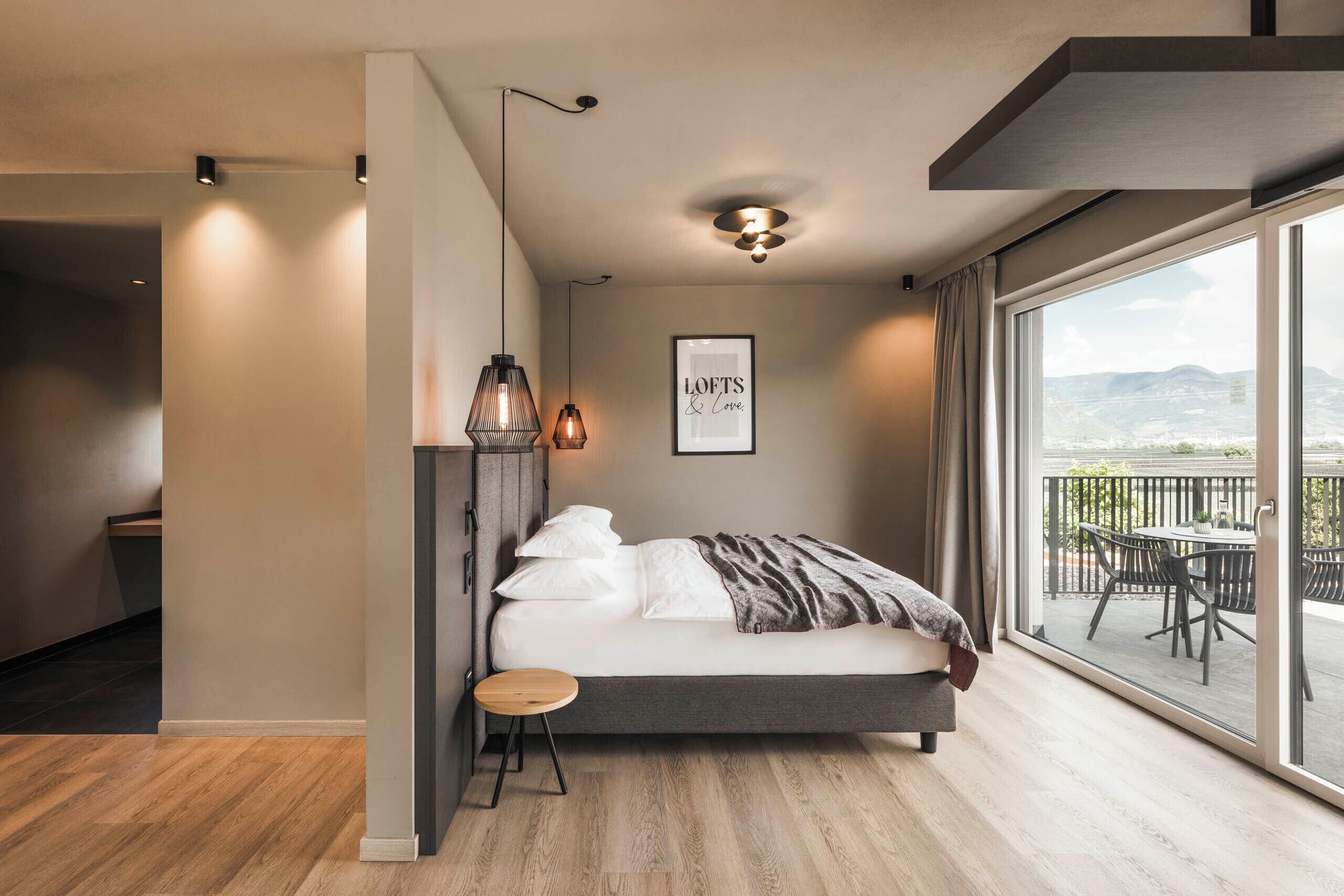 Ein modernes Schlafzimmer mit großem Fenster, einem Bett, einem kleinen Hocker und einem Deckenventilator.