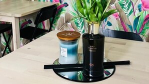 Taula amb fons de paper pintat floral, una espelma i un ram de flors.
