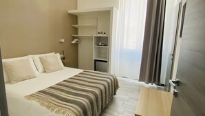 Una habitació d'hotel amb un llit, una taula de nit, un armari i un aire condicionat.