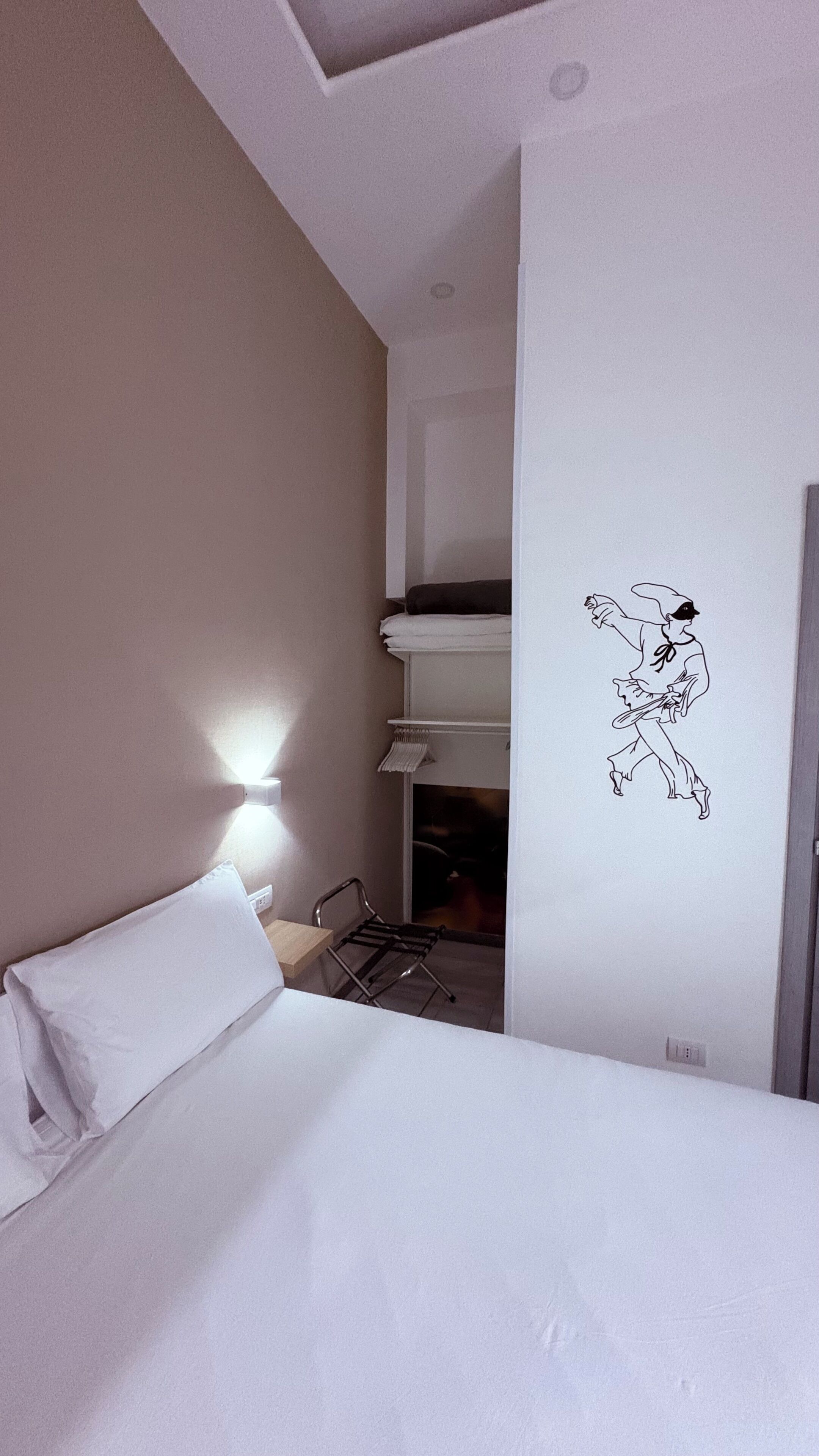 A hotel room with a bed, a wall-mounted light, a bunk bed, and a wall decal.