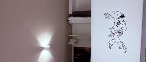 A hotel room with a bed, a wall-mounted light, a bunk bed, and a wall decal.