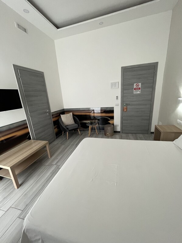 A modern hotel room with a large bed, a desk, a chair, and a TV. - A casa di Gemma (Naples)