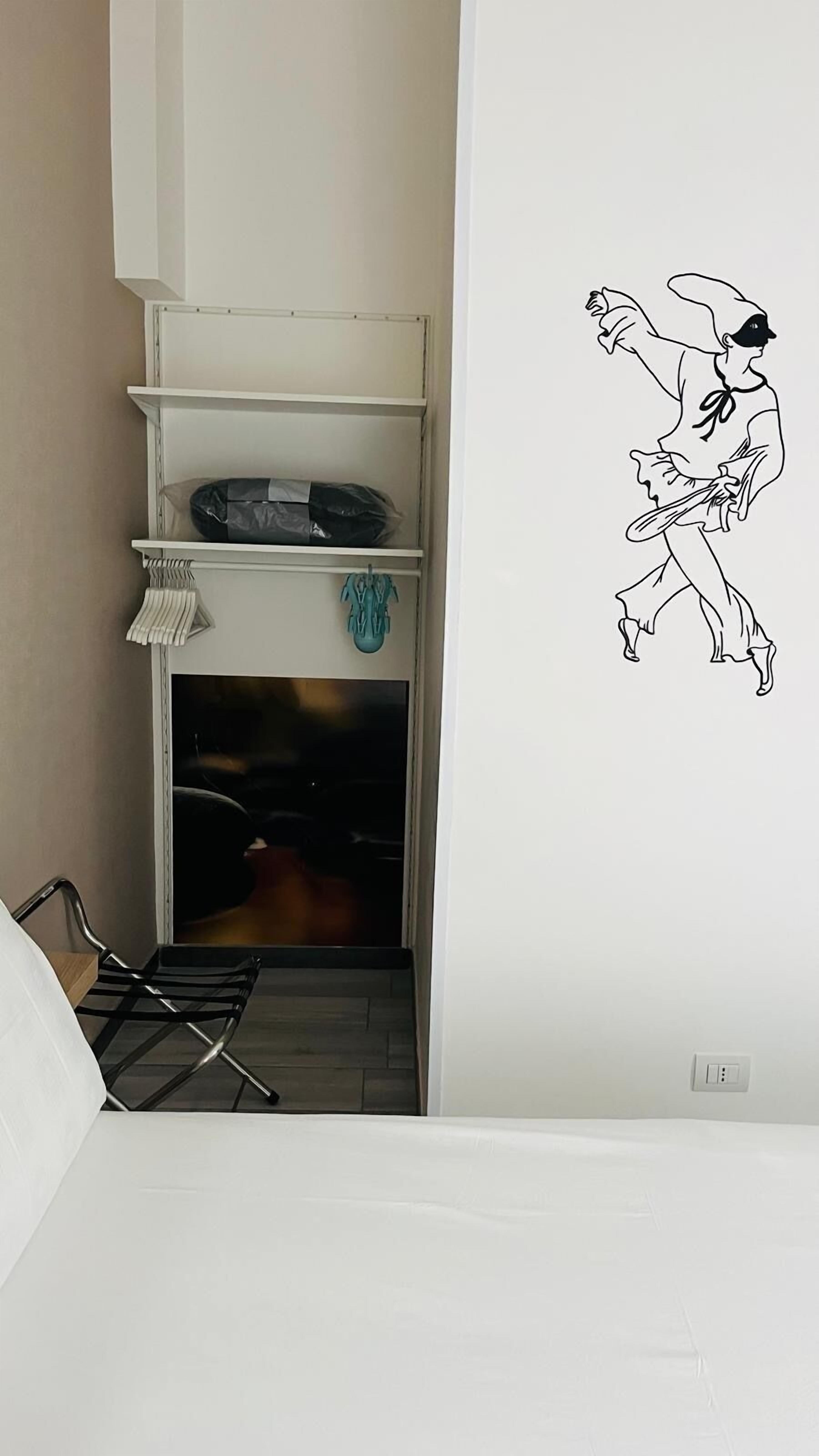 A room with a fireplace, a white shelf with a black object, and a wall decal of a cartoon character.