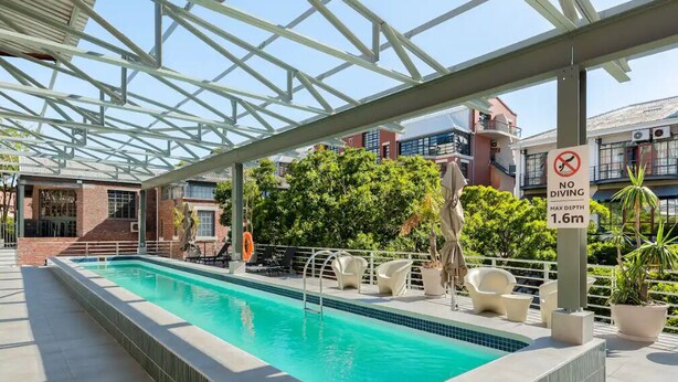 A swimming pool with a no diving sign, surrounded by lounge chairs and potted plants. - Artistic Spacious Luxury Loft, a 10 min. walk to V&A Waterfront & fine dining! (Cape Town)