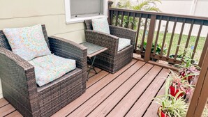 Una terraza de madera con muebles de mimbre y plantas en macetas.