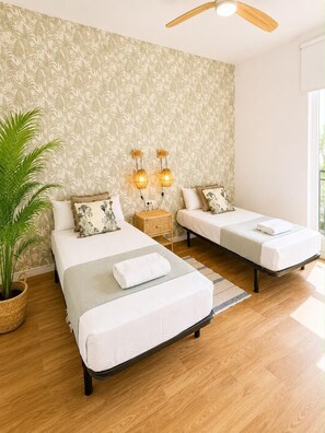 A bedroom with two beds, a nightstand with lamps, a potted plant, and a ceiling fan. - Valencia Luxury - Malvarrosa Beach (Valencia)