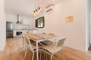 A modern kitchen with a wooden table, white chairs, and a built-in oven. - Valencia Luxury - Malvarrosa Beach (Valencia)