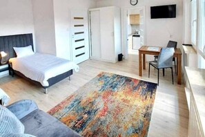 Relax in this serene bedroom with a large bed, gray sofa, and colorful rug.
