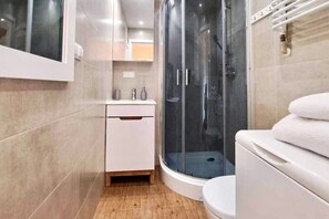 Bathroom features a curved shower enclosure, toilet, and ample storage.