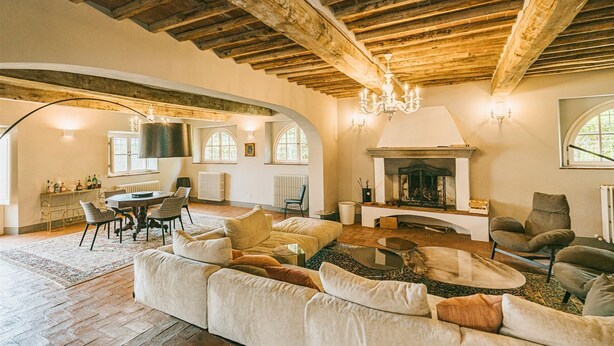 A spacious living room with a fireplace, wooden beams, and a dining area with a table and chairs. - Villa Anjelica - Ten Bedroom Villa, Sleeps 22 (Lucca)