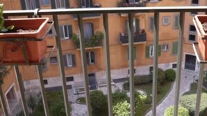 Un balcon orné de jardinières en terre cuite, d’où l’on peut admirer un immeuble à plusieurs étages, doté lui aussi de balcons et de fenêtres.