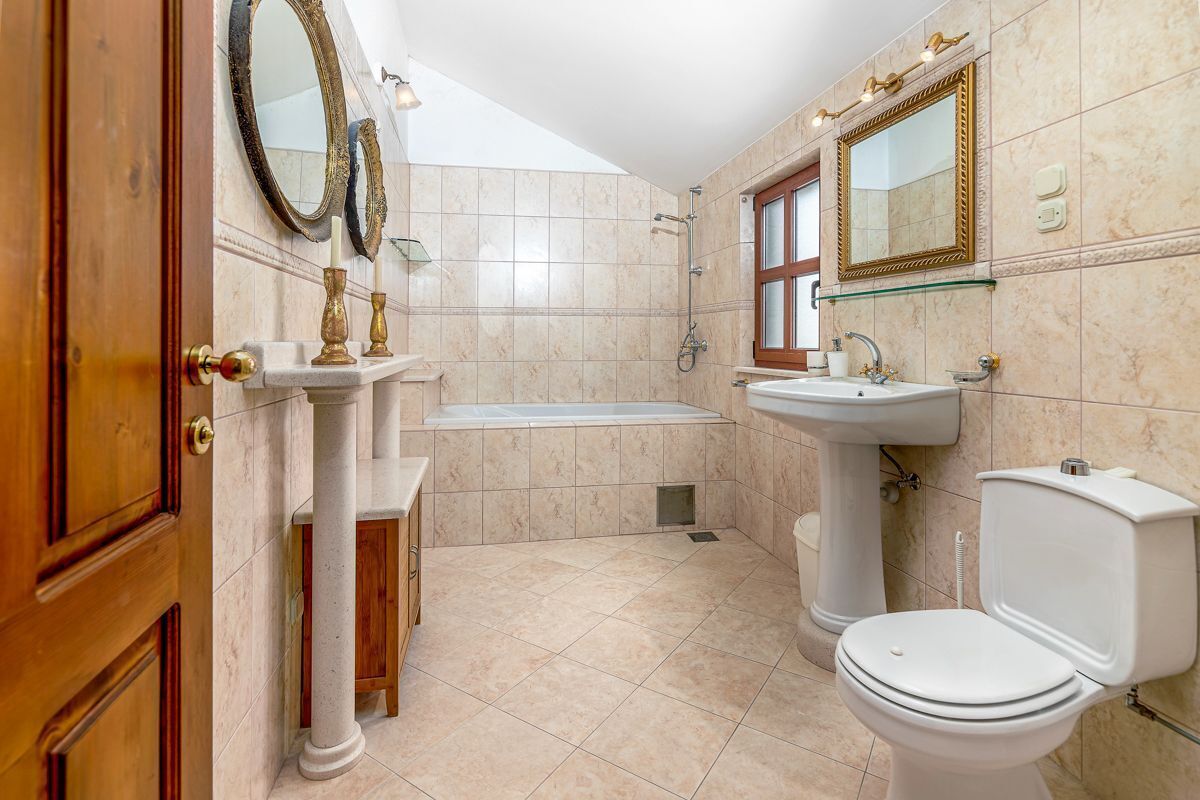 A bathroom with a bathtub, toilet, sink, and two mirrors.