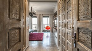 Een hal met decoratieve deuren, een kroonluchter en een rode stoel.