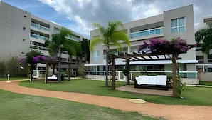 A modern building with multiple floors, outdoor seating areas, and greenery. -  OZPED Flats Particulares Brisas do Lago (Brasília)