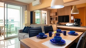 A modern kitchen with a dining area, a coffee machine, and a TV. -  OZPED Flats Particulares Brisas do Lago (Brasília)