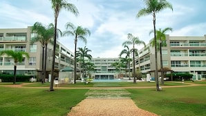 A modern hotel with a central courtyard, palm trees, and a pool. -  OZPED Flats Particulares Brisas do Lago (Brasília)
