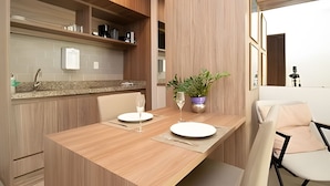 A modern kitchen with wooden cabinets, a granite countertop, and a dining area with a wooden table and chairs. -  OZPED Flats Particulares Brisas do Lago (Brasília)