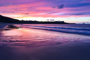 A beach with waves, a sunset, and distant hills. - Tuath na Mara - Three Bedroom Villa, Sleeps 9 (Doagh Beg)