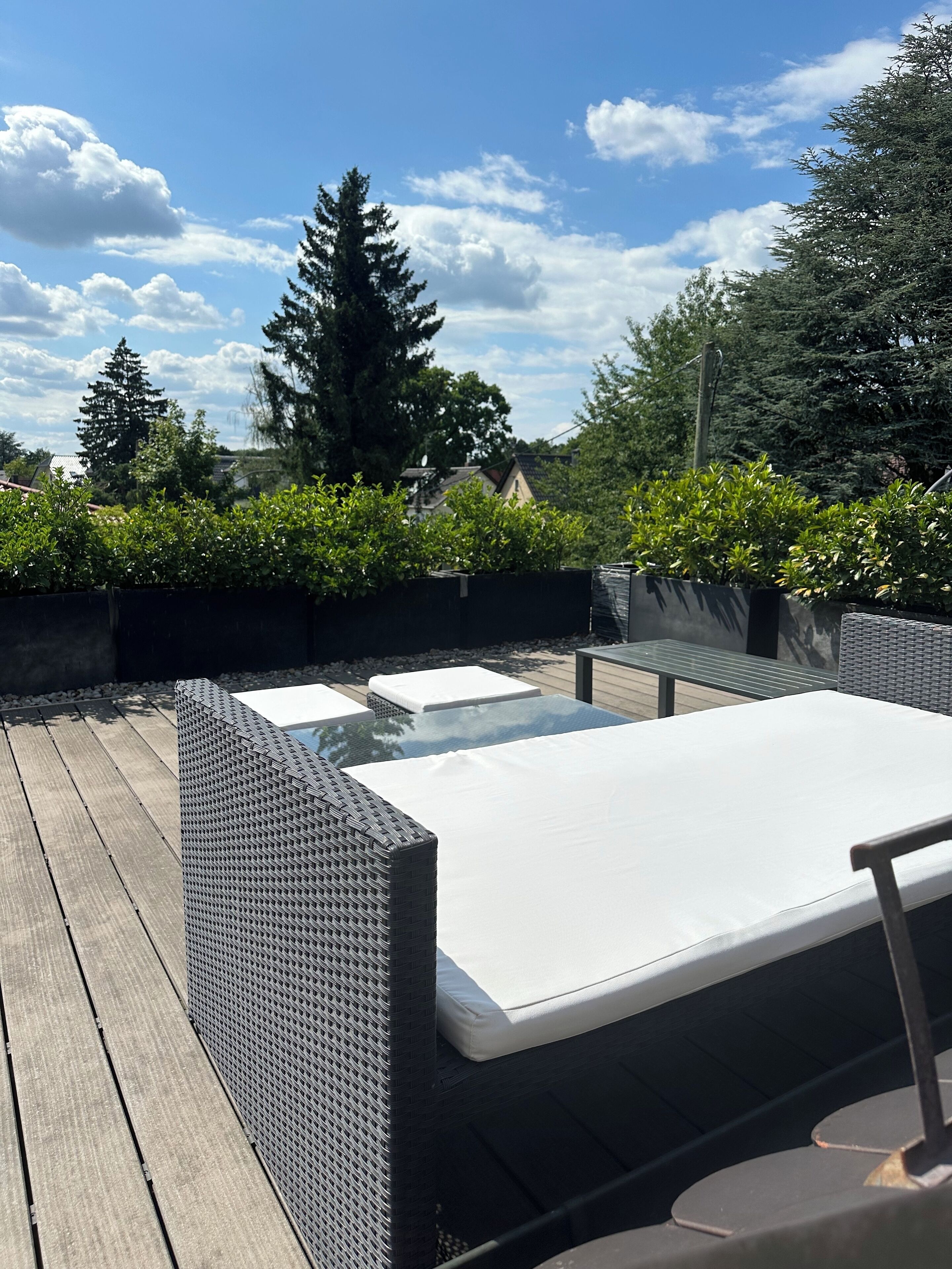 Eine Terrasse im Freien mit einem Tisch aus Glas und einer gepolsterten Bank.