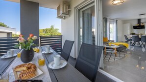 A balcony with a dining table set for breakfast, including croissants and orange juice. - Domus Alba Apartments - Apt 1 (Pula)