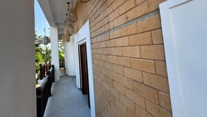 A corridor with a brick wall, hanging wicker lamps, and a white door. - Room in Villa - Surf 247 Weligama Hotel (Weligama)