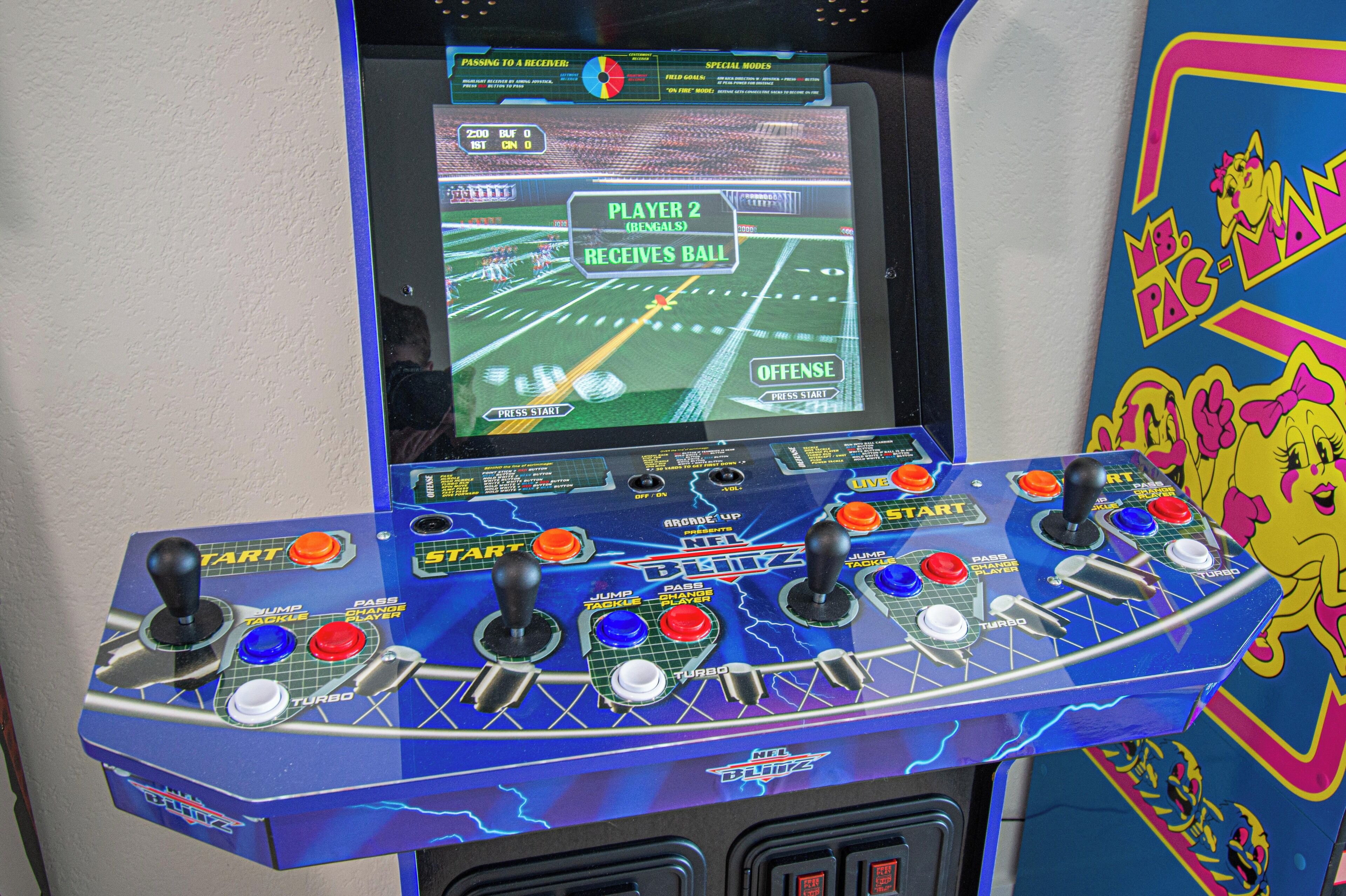 A video game arcade machine with multiple joysticks and a screen displaying a football game.