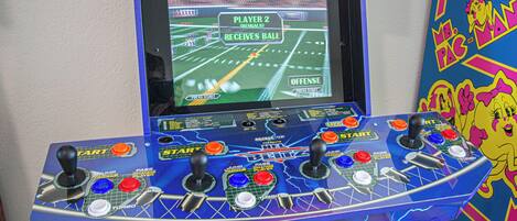 A video game arcade machine with multiple joysticks and a screen displaying a football game.
