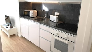 Una cocina moderna con armarios blancos, encimera negra, microondas, tostadora y estufa.