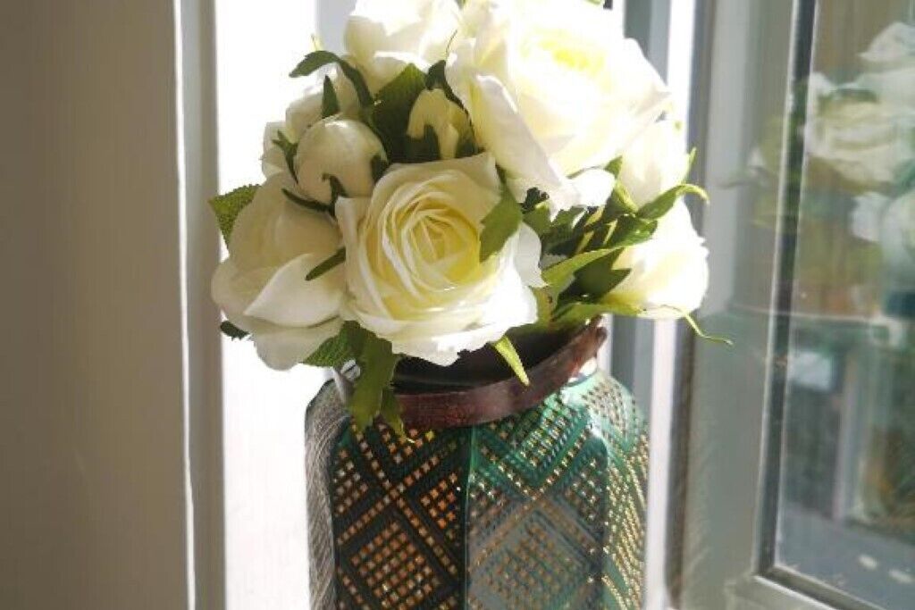 A vase with a geometric pattern containing white roses.