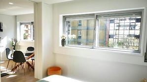 Una habitación de hotel moderna con cama, escritorio y ventana con vistas a edificios.